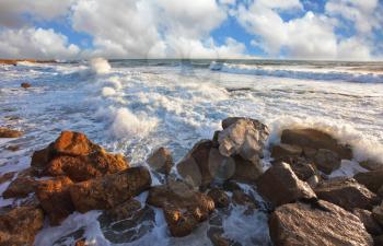 Tel Aviv, sunset, spring. Magnificent storm in the Mediterranean. Storm waves crash against the rocks on the breakwater embankment. 