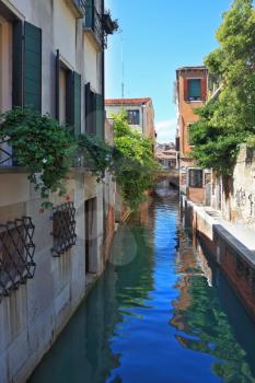 Eternal fantastic Venice. Narrow street - the channel. In water the dark blue sky is reflected. Windows of ground floors are closed by figured lattices.