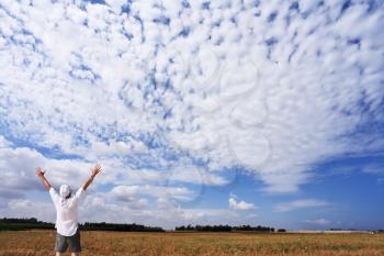 The man in a white shirt in delight from beauty of the cloudy sky
