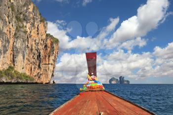 The Thai excursion boat floats to ocean island. The boat nose is decorated by multi-colored and bright silk scarfs