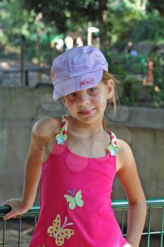 The lovely seven-year girl in a pink sundress and a satiny cap
