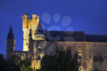 Palace of Spanish kings Alcazar in Segovia in twilight on a background of the cloudy sky