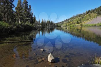 Shallow quiet blue Mammoth Lake among the mountains and pine forests