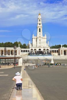 The grand memorial and religious complex in the small Portuguese town of Fatima. A woman in a hat on his knees crawling on a specially laid track to the temple