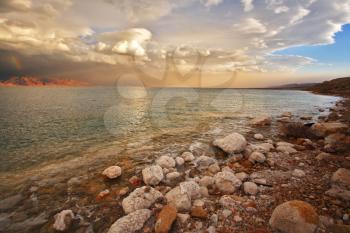 Coast of the Dead Sea in Israel in a spring thunder-storm. Coastal stones are covered by salt