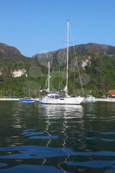 Romantic white yacht in the azure bay, surrounded by wooded mountains