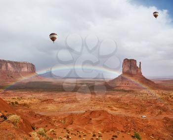 Balloons under storm clouds. Monument Valley - Navajo Reservation during the summer thunderstorms. The magnificent rainbow over the famous red sandstone Mittens
