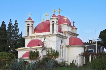 Greek Orthodox Monastery of the Twelve Apostles. Bright pink dome, whitewashed walls of the holy temple on the shore of the Sea of Galilee
