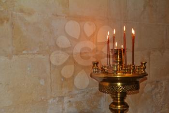 Bronze Floor candlestick with burning candles. Background - a stone wall