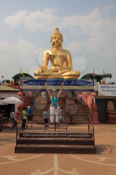 The famous Golden Triangle. Golden Buddha statue shining in the sun. Place on the Mekong River, which borders three countries - Thailand, Myanmar and Laos. Happy tourist posing for a photograph with i