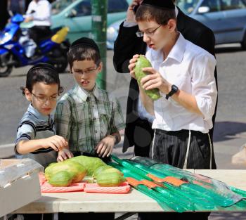 Bnei Brak - September 22: A group of Jewish boys in velvet skullcaps chooses ritual plant citron before the holiday of Sukkot. Holiday city market September 22, 2010 in Bnei Brak, Israel
