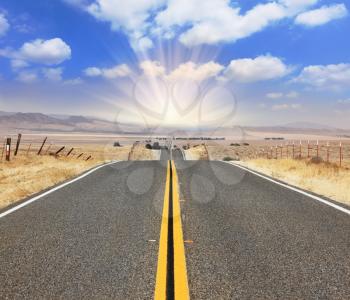 The bright sun illuminates the ideal  highway. The magnificent road through boundless to the desert