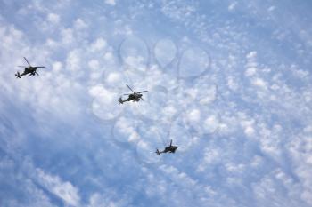 Three fighting helicopters beautifully flying on military-air parade in the cloudy sky