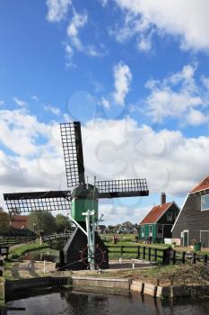 Ancient rural street. The village- museum in Holland. A picturesque windmill, the channel and ancient rural lodges with red roofs
