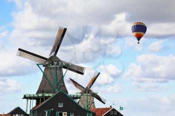 Picturesque windmills, flying colorful balloon and the old village houses with red roofs