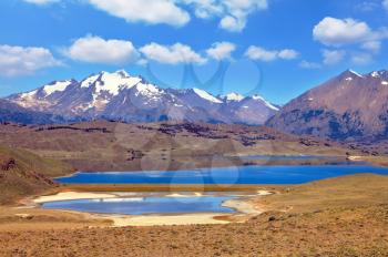 The wide valley surrounded by snow-capped mountains. Two small oval lake. Argentine Patagonia