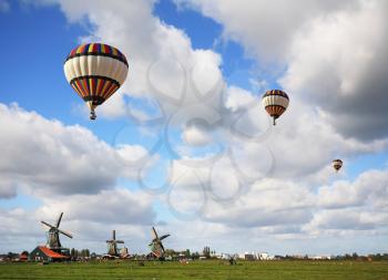 Bright striped balloon flies over the flat plains and windmills