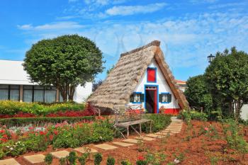 Charming white cottage with a thatched roof and gable small garden with flowers. Picturesque house-museum of the first colonists to Madeira. 