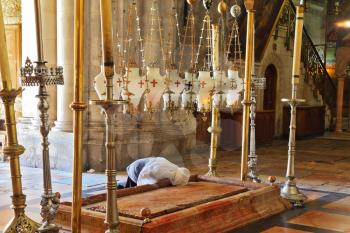 Church of the Holy Sepulcher in Jerusalem. Pilgrim prays in a white veil over the Stone of Unction