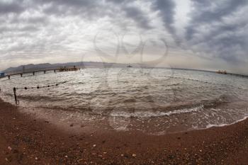 Early spring on a beach of Red sea in Israel. The safe place for bathing is fenced. It is photographed by an objective the Fish eye