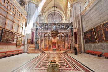 Church of the Holy Sepulcher in Jerusalem. Huge beautifully decorated hall in front of the Edicule. Hall lit sunlight through windows in the dome and ceiling lamps. In the center is a stone vase - th
