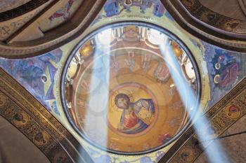 Gorgeous round arch ceiling lit by two bright rays of the sun. On the ceiling in the Hall of the Holy Sepulchre image of Christ the Savior