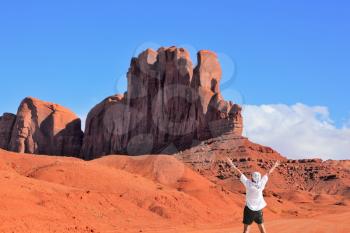 The enthusiastic tourist in a white shirt in Monument Valley. The famous monolith of red sandstone - Camel ..