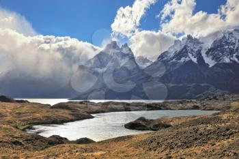 The majestic landscape of Patagonia. National Park Torres del Paine. Fog envelops the mountain range and is reflected in the cold water of the lake