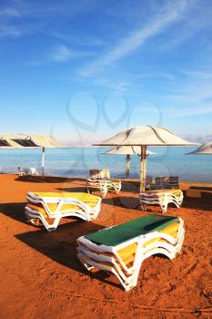 Beautiful sunny day at a beach resort. The Dead Sea, the green beach chairs and umbrellas waiting for tourists