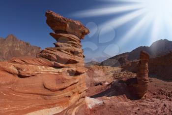 The sparkling sun above interesting natural forms of sandstone hoodoos in mountains of Eilat, Israel