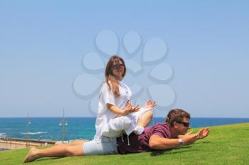  A lovely summer day, the family is happy. Young couple relaxing on the grass by the sea. Charming young woman is pregnant