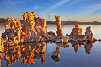  Outliers -  bizarre calcareous tufa formation  reflected in the mirrored surface of the water. A picturesque sunset at Mono Lake. Yosemite National Park, USA