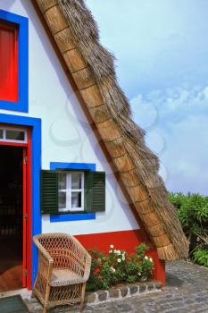 Traditional rural landscape. The village - Museum of the Portuguese island of Madeira. The little white house with a triangular thatched roof and a red door.