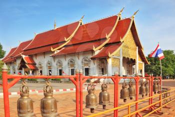 Gold-plated entrance to a Buddhist temple in northern Thailand. The roof of the temple - red with gilt edges. Fencing of the temple is decorated with bronze bells