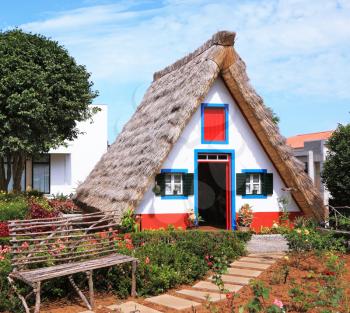 Traditional rural landscape. The little white house with a triangular thatched roof and a red door. The village - Museum of the Portuguese island of Madeira
