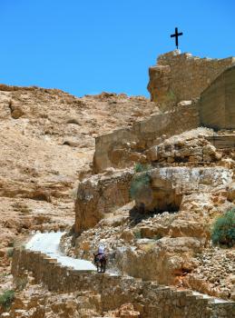 On the road, paved with stone, raised on a donkey woman - a pilgrim dressed in white. Wadi Kelt, the road to the monastery of St. George