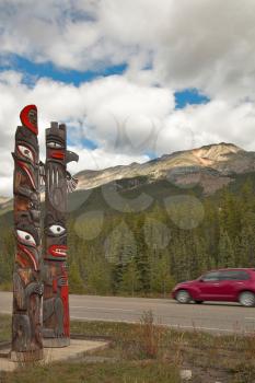 Totem columns, the red car on highway in mountains