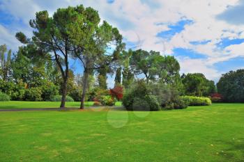 The famous Garden Park Sigurta in Italy. The bright green grassy lawn is surrounded with well-groomed trees