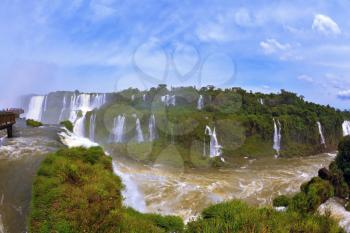 Raging and roaring water in the waterfalls of Iguazu. Turbid yellow-brown waves flow down. The Brazilian side