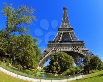 Huge and beautiful Eiffel Tower. At the foot of the tower is designed park with paths and pond. The picture was taken Fisheye lens