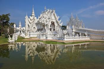 White fairy palace. Built in the style of the new Thai architecture. Castle beautifully reflected in a pond with live fish