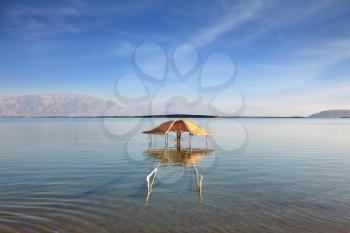 The magnificent beach on the Dead Sea. The picturesque gazebo for protection from the sun reflected in water