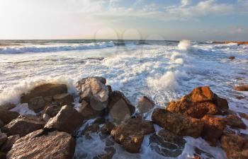 Tel Aviv, sunset, spring. Magnificent storm in the Mediterranean. Storm waves crash against the rocks on the breakwater embankment. 
