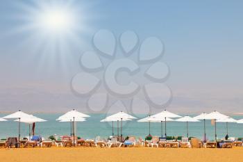 Sun beds, chairs, umbrellas and awnings on the beach luxury hotel on the Dead Sea in Israel. Sunny spring day