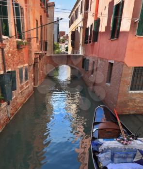 Eternal fabulous Venice. The narrow street - channel brightly lit afternoon sun. Against the wall approached by gondola
