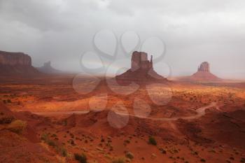 The grand landscape of Monument Valley. Famous Mittens of red sandstone in a fog after the storm and a rainbow in the sky