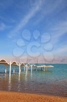  Descent in water is issued by a picturesque canopy and a handrail. Magnificent beach on the bank of the Dead Sea.