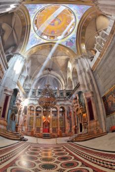 Gorgeous huge marble hall in the Holy Sepulchre lit bright sun. On the walls of the hall paintings on biblical themes. Entry to the altar of the draped red curtain. Carpet on the floor is paved in mar