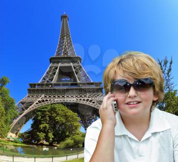 Beautiful blond boy having fun chatting with friends on a cell phone. Background - the Eiffel Tower. The picture was taken Fisheye lens