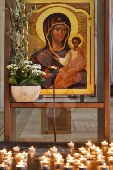  An icon of the Virgin with the baby and a burning candle before it(her)